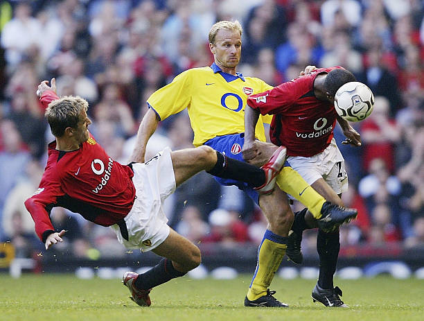 MANCHESTER, ENGLAND - SEPTEMBER 21: Quinton Fortune and Phil Neville of Man Utd clash with Dennis Bergkamp of Arsenal during the FA Barclaycard Premiership match between Manchester United and Arsenal at Old Trafford on September 21, 2003 in Manchester, England. (Photo by Shaun Botterill/Getty Images)